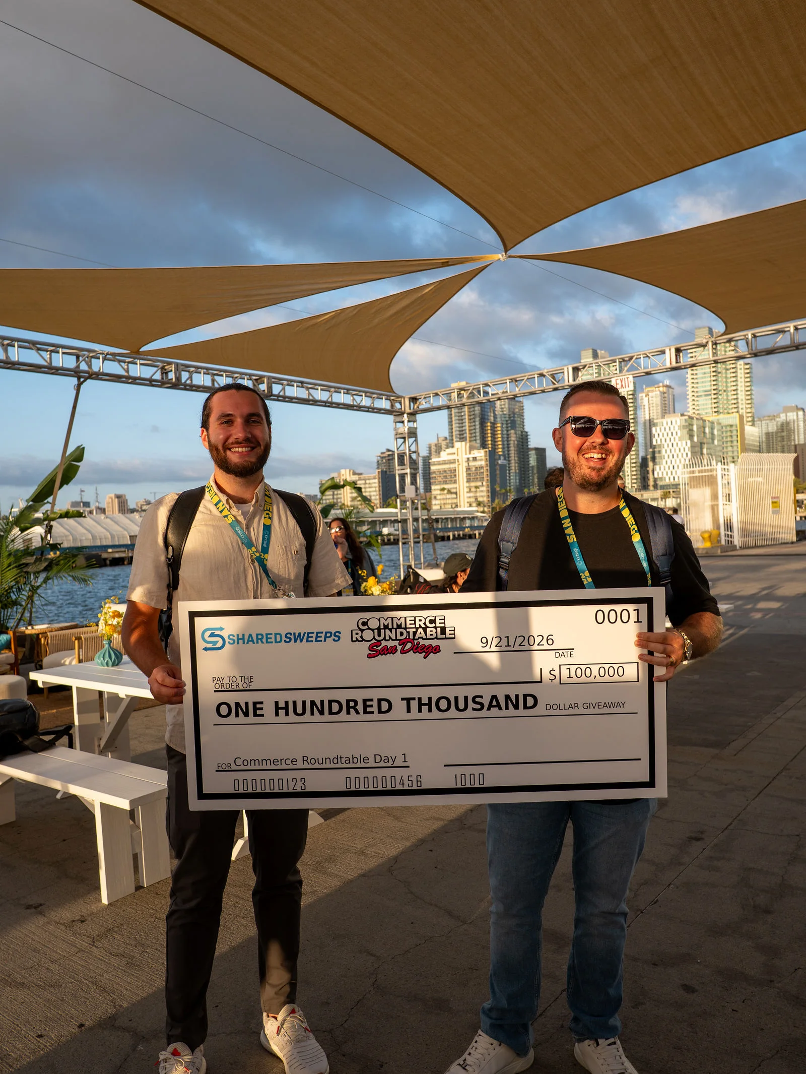 Two attendees smile while posing with a giveaway check.