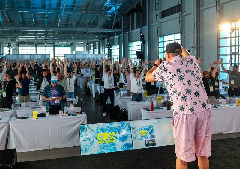 Attendees raising their hands as a host leads an energetic moment from the stage