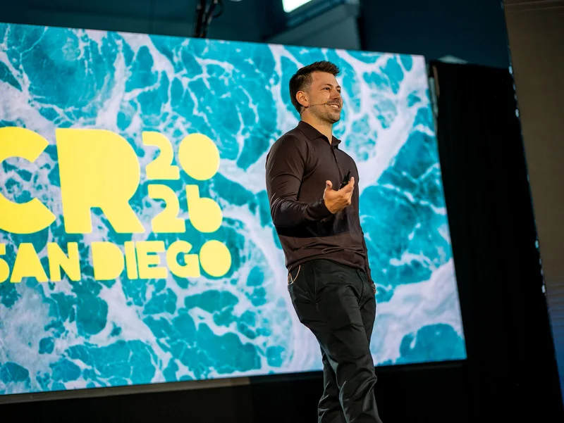 A speaker sharing ideas in front of the turquoise and yellow San Diego backdrop