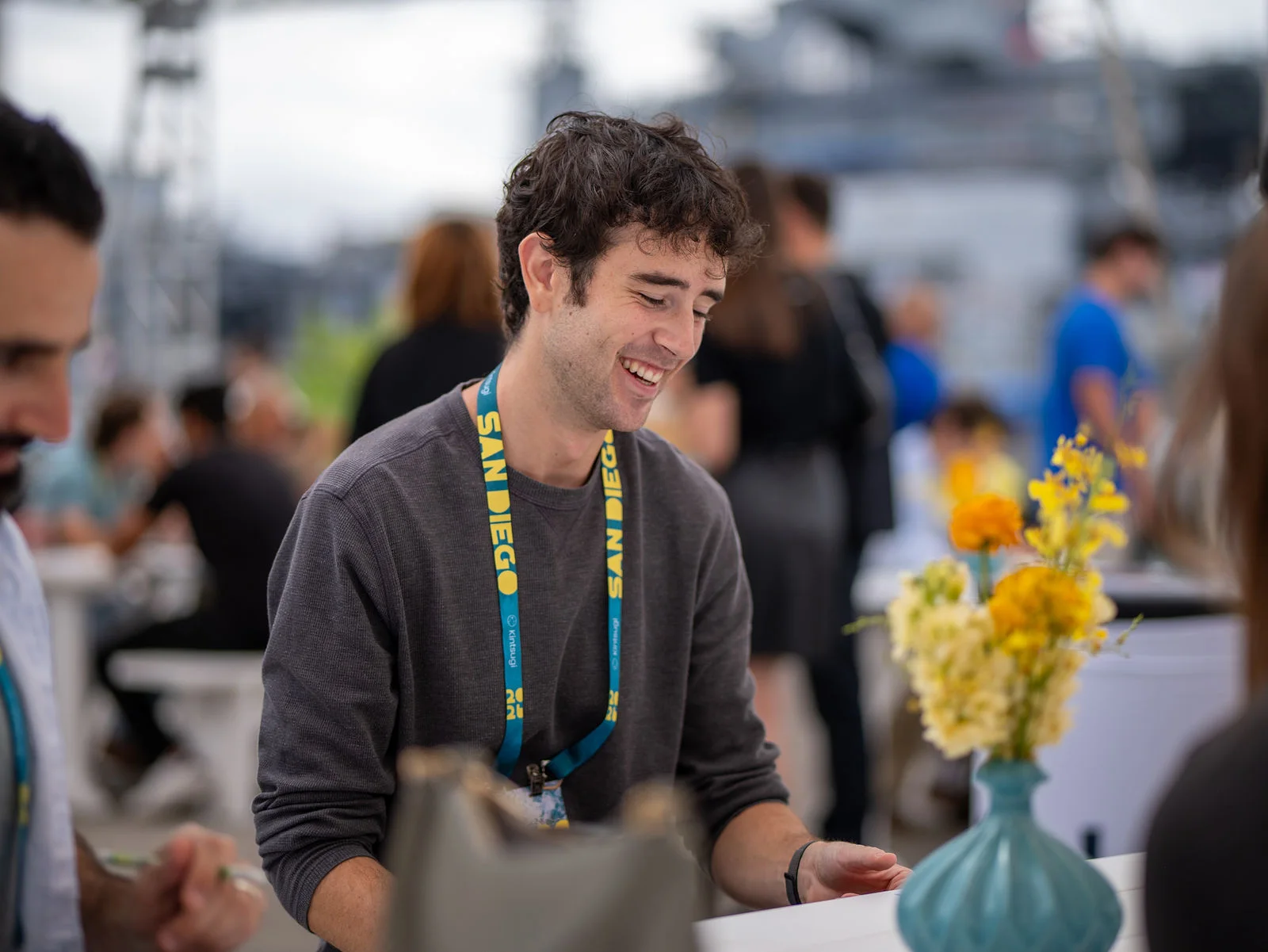 An attendee laughing during a conversation at a waterfront table