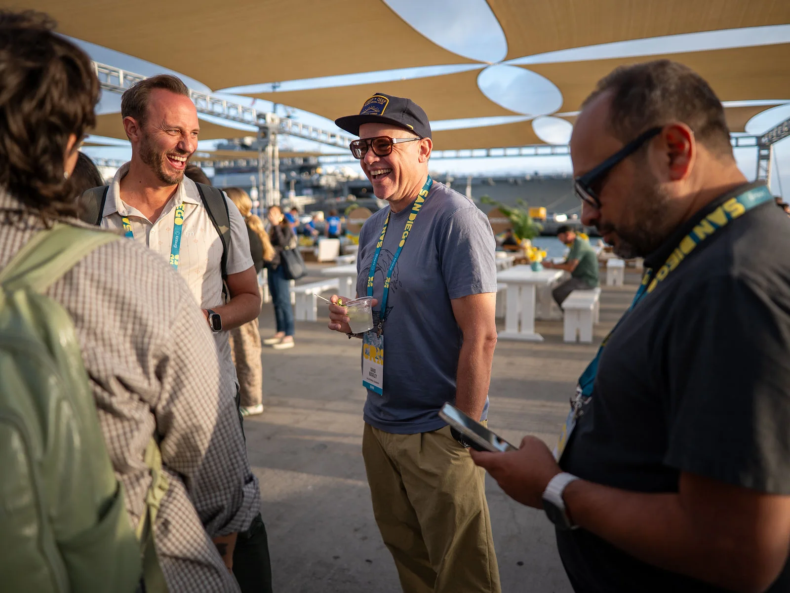 A group sharing a laugh during a golden-hour conversation by the harbor